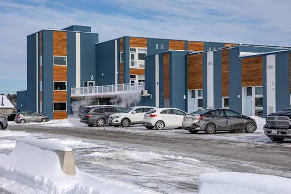 A parking lot with cars and a building in the background.