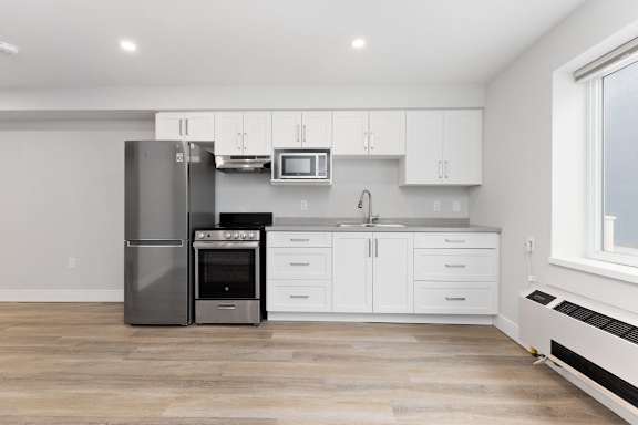 A modern kitchen with a stainless steel refrigerator, oven, and microwave.