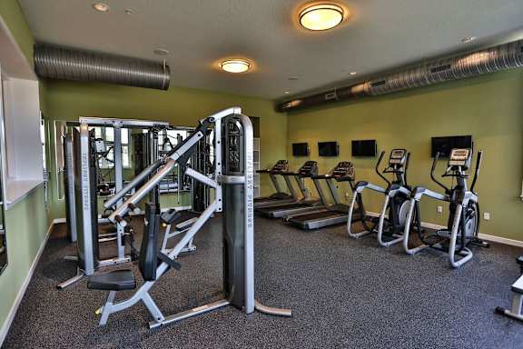 A gym with a variety of equipment including treadmills, weights, and exercise bikes.