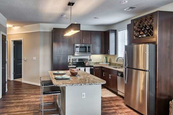 A modern kitchen with dark wood cabinets and stainless steel appliances.