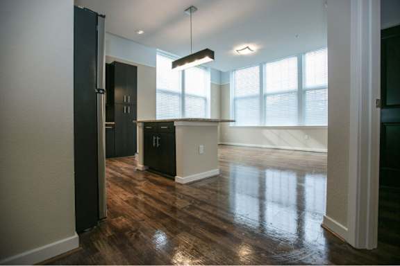 A kitchen with black cabinets and a wooden floor.