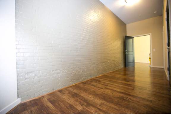 A room with a white brick wall and wooden floor.
