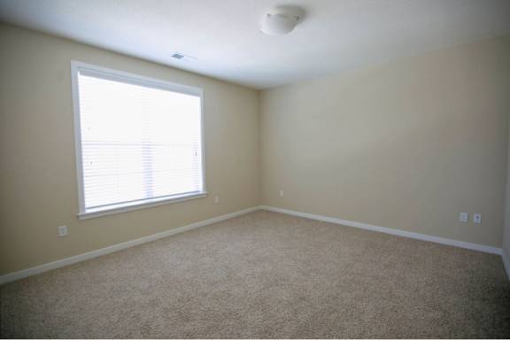 A room with a window and carpeted floor.