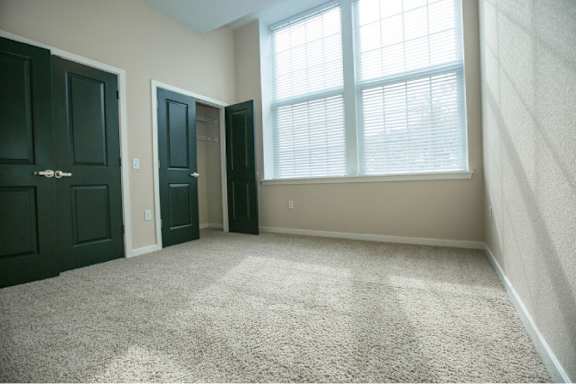 A room with carpeted floor and two doors.