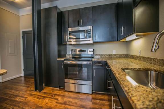 A modern kitchen with black cabinets and stainless steel appliances.
