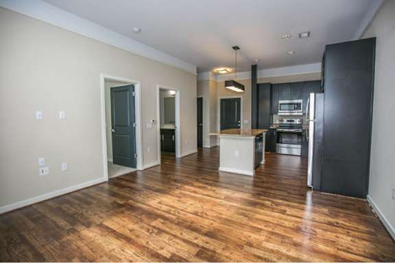A kitchen area with a refrigerator, sink, and cabinets.