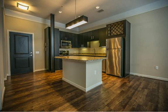 A kitchen with a stainless steel refrigerator and wooden floors.