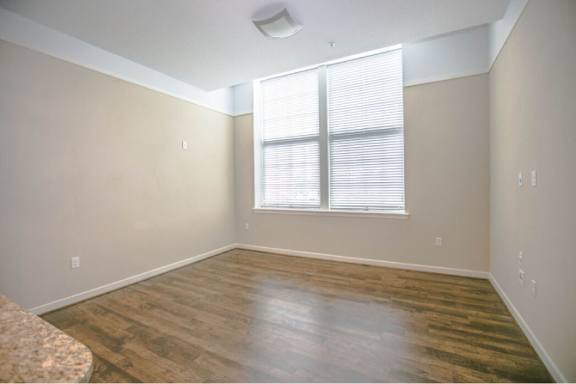 A room with wooden flooring and a window with blinds.