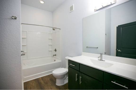 A white toilet sits in a bathroom with black cabinets.