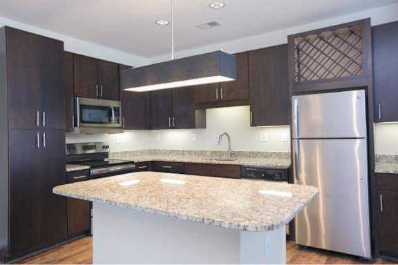 A kitchen with a granite countertop and stainless steel appliances.