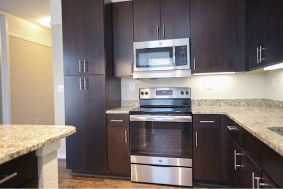A kitchen with dark brown cabinets and stainless steel appliances.