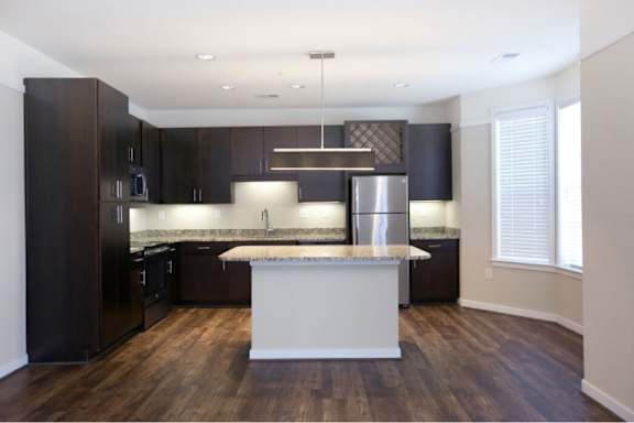 A modern kitchen with dark wood cabinets and a white island.