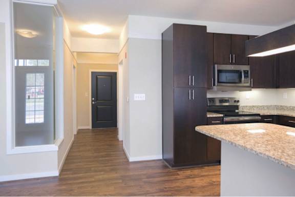 A kitchen with dark brown cabinets and a granite counter.