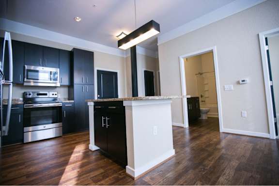A kitchen with black cabinets and a white island.