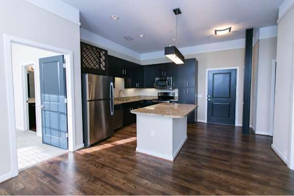 A kitchen with a white island and dark wood floors.
