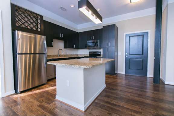 A kitchen with a refrigerator, cabinets, and a countertop.