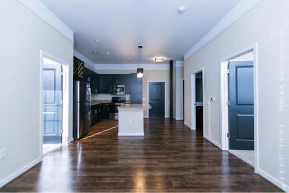 A spacious kitchen with dark wood floors and white walls.