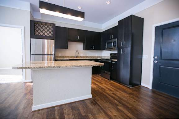 A kitchen with black cabinets and a granite countertop.