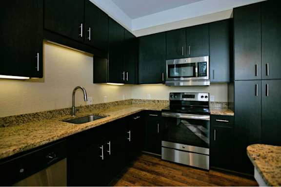 A kitchen with black cabinets and a granite countertop.