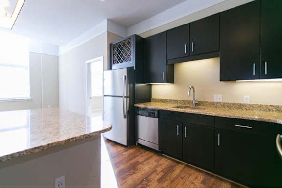 A kitchen with black cabinets and a granite countertop.