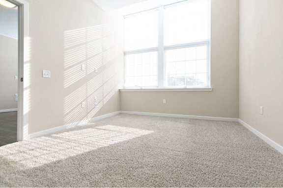 A room with a carpeted floor and a large window.