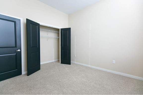 A room with a carpeted floor and a black door.
