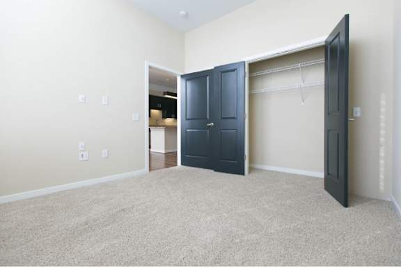 A room with a carpeted floor and a large open doorway leading to another room.
