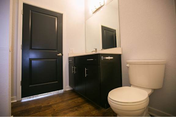 A white toilet sits next to a black cabinet in a bathroom.