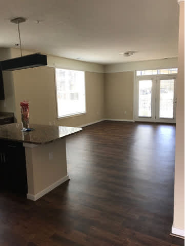 A kitchen with dark wood floors and white walls.