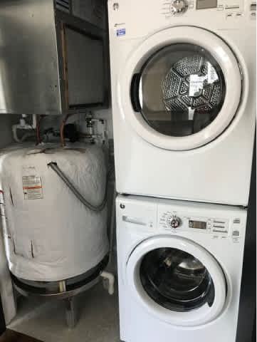 A white washing machine is stacked on top of a white dryer.