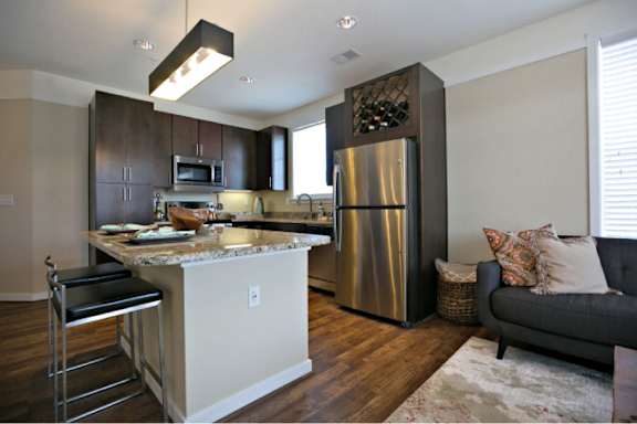 A modern kitchen with a refrigerator, microwave, and a countertop with a sink.