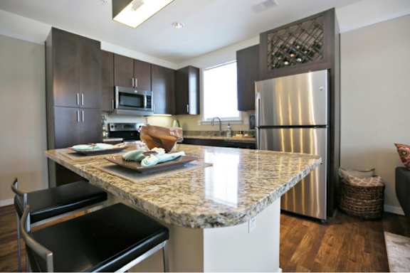A kitchen with a granite countertop and stainless steel appliances.