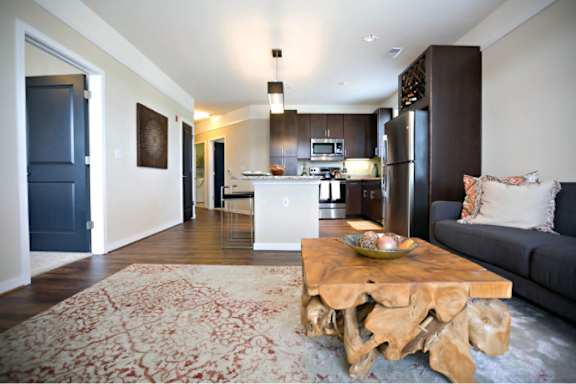 A modern living room with a wooden coffee table and a grey couch.