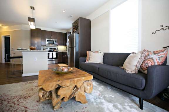 A modern living room with a couch, coffee table, and kitchen area in the background.
