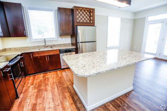 A kitchen with a granite countertop and wooden cabinets.