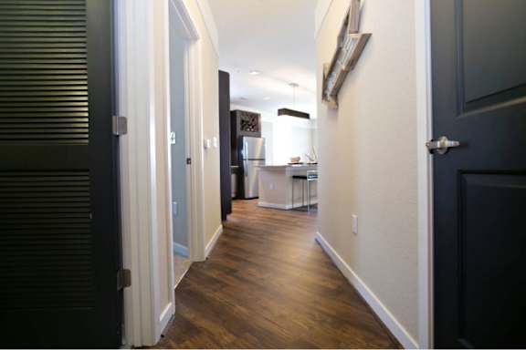 A hallway with a black door on the left and a white door on the right.
