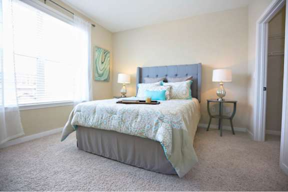 A bedroom with a bed, two lamps, and a nightstand.