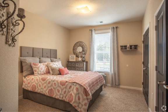 A bedroom with a large bed and a window with curtains.