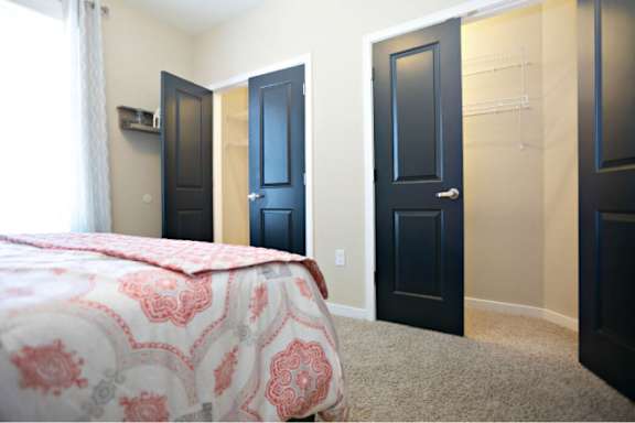 A bedroom with a bed, two doors, and a window.
