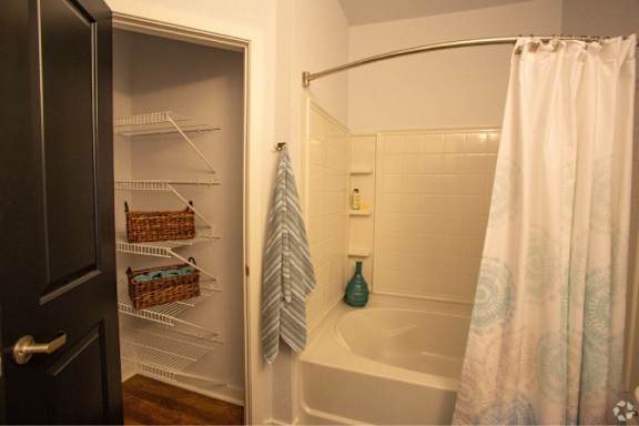 A bathroom with a white tub and a white shower curtain.