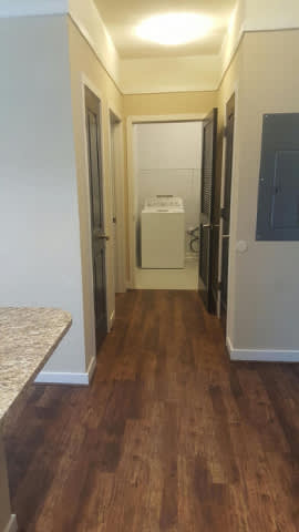A hallway with wood flooring and white walls.