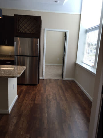 A kitchen with a refrigerator and a doorway leading to another room.
