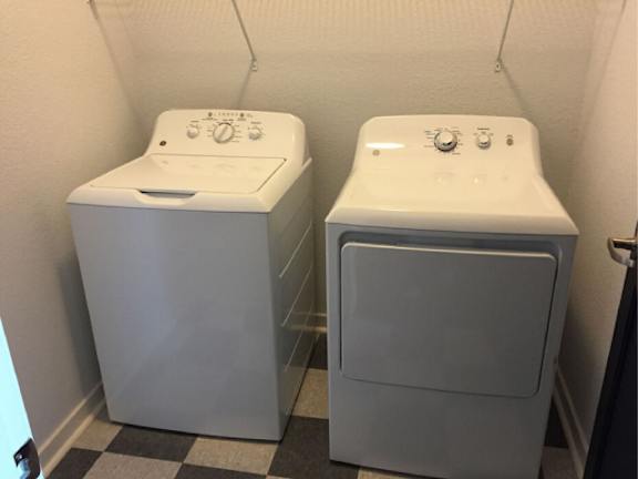 Two white washing machines in a small room.