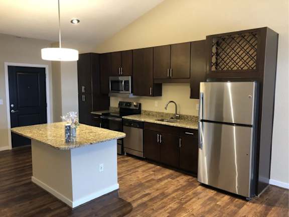 A kitchen with a granite countertop and stainless steel appliances.
