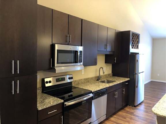 A kitchen with dark wood cabinets and stainless steel appliances.