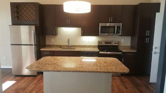 A kitchen with brown cabinets and a granite counter.