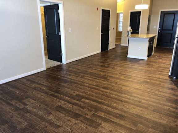 A room with wooden flooring and a kitchen island in the middle.