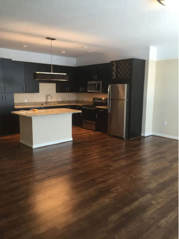 A kitchen with dark cabinets and a wooden floor.