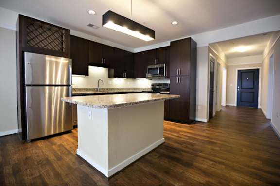 A kitchen with a white island and dark wood cabinets.