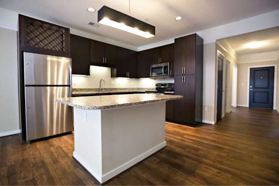A modern kitchen with dark wood cabinets and a stainless steel refrigerator.